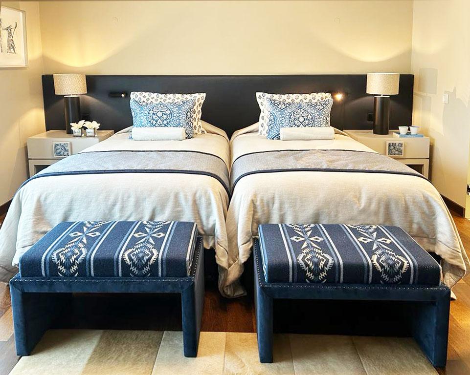  Bedroom design featuring a dark blue wall-to-wall headboard, custom-designed nightstands with built-in tiles, and a beige bedspread